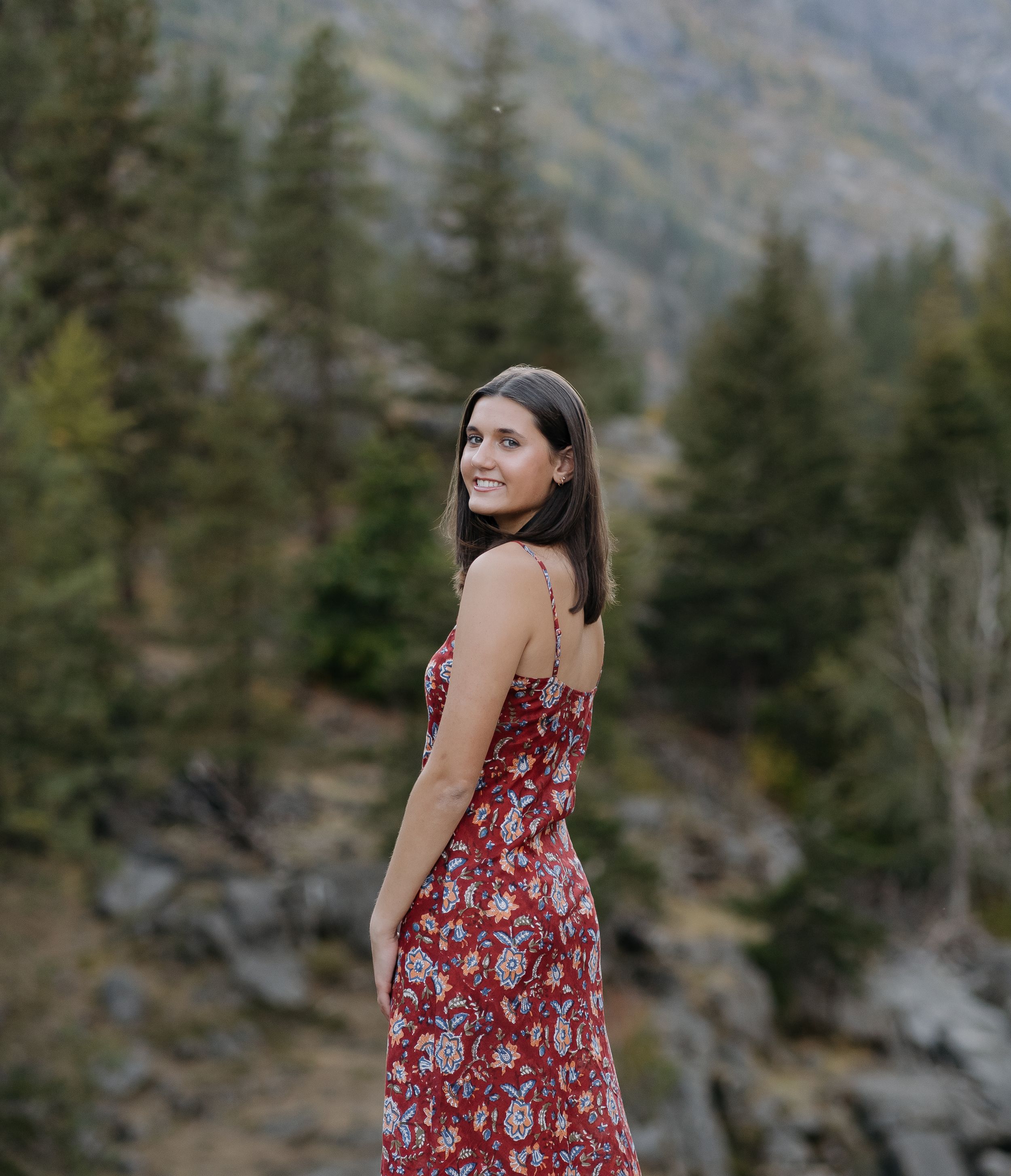 Mountain landscape frames a portrait in a flowing red floral dress.