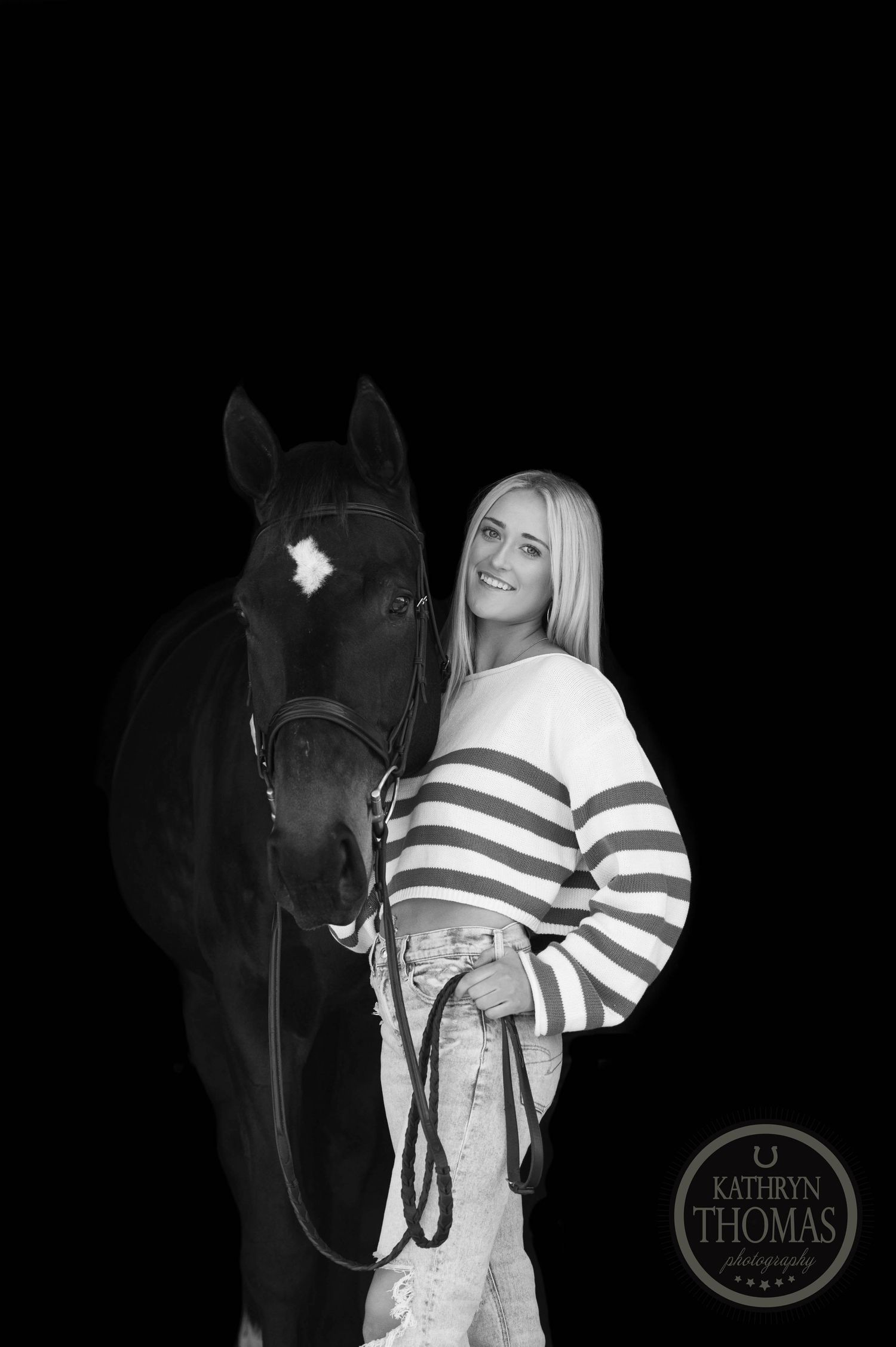 Black and white portrait of horse and person wearing striped sweater against dark background.