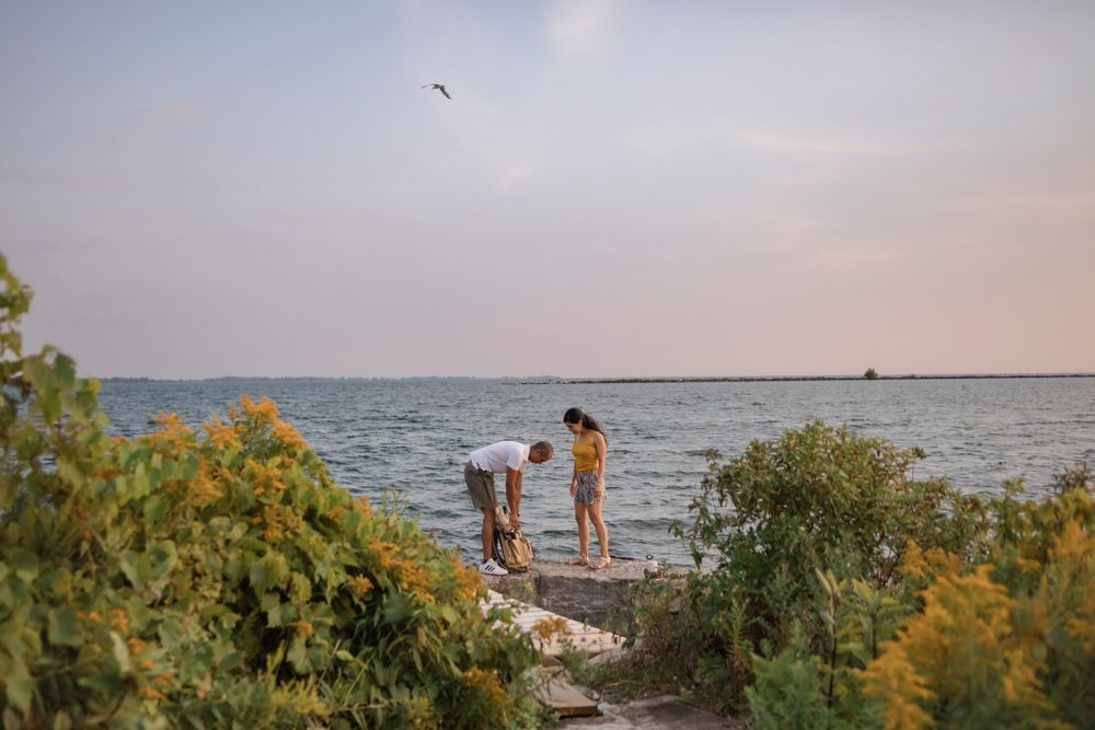 Couple arrives to a breakwall of Lake Ontario, preparing to go fishing. Kingston, ON.