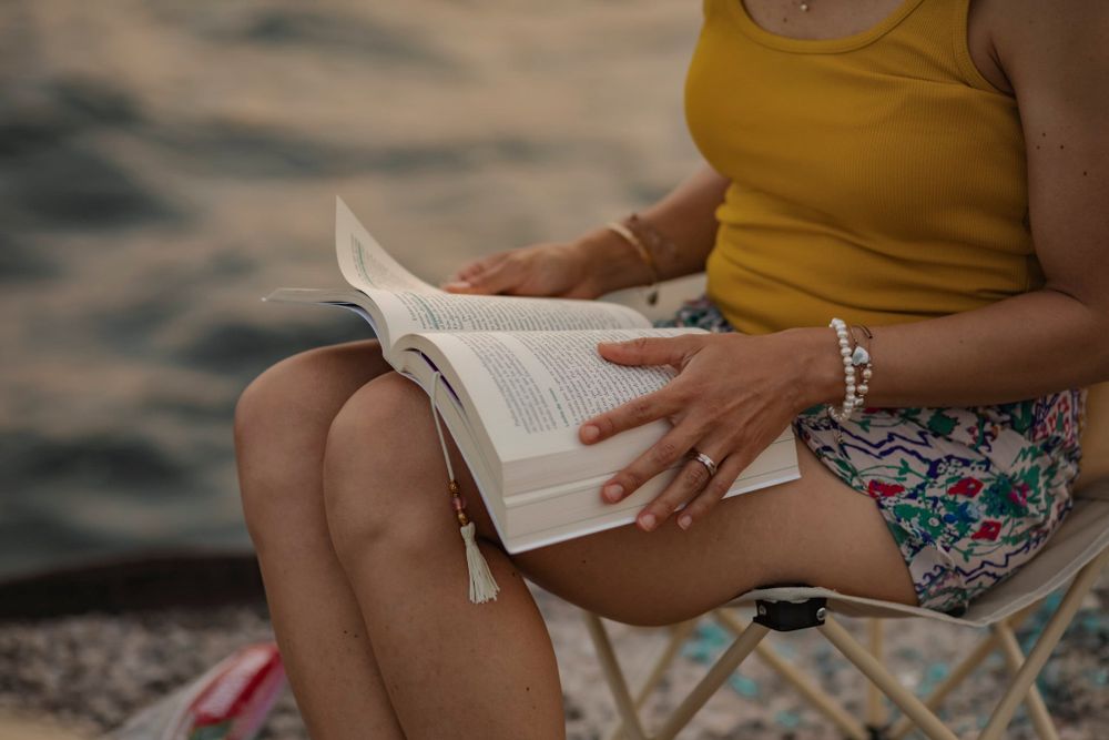 Detail of soman reading a book on the shoreline of Lake Ontario.