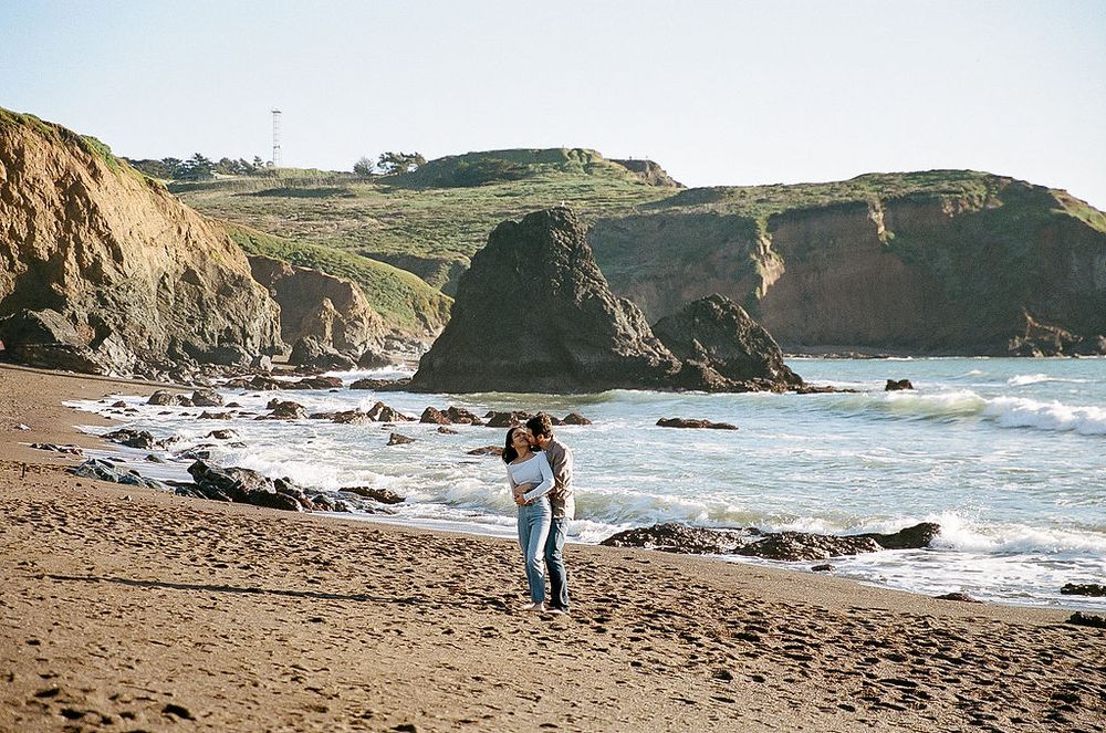 Scenic coastal view of rugged cliffs and rocky beach along the Pacific Ocean with waves crashing on the shore.