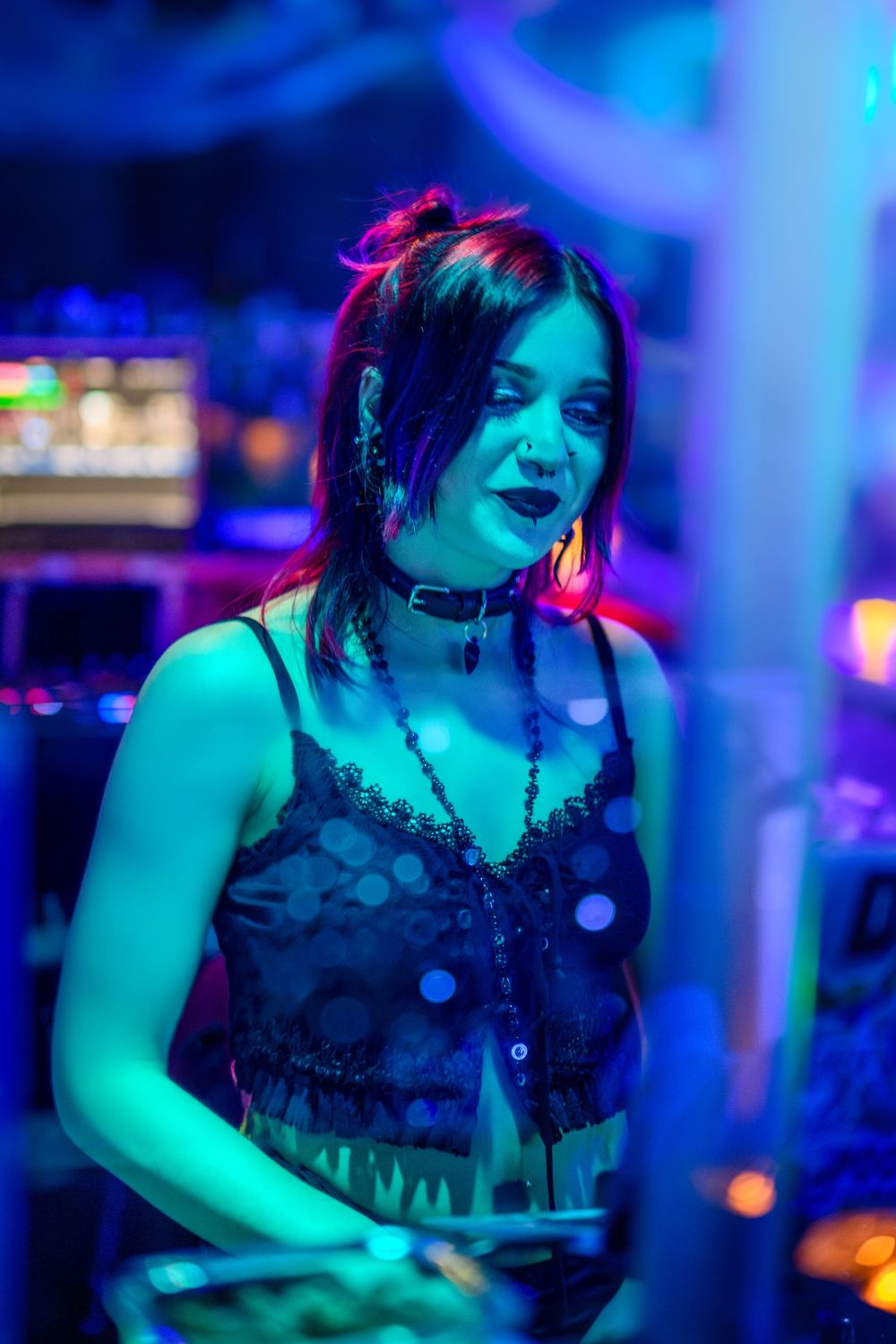 Young woman DJ performing under vibrant blue and purple neon lights at a nightclub event.