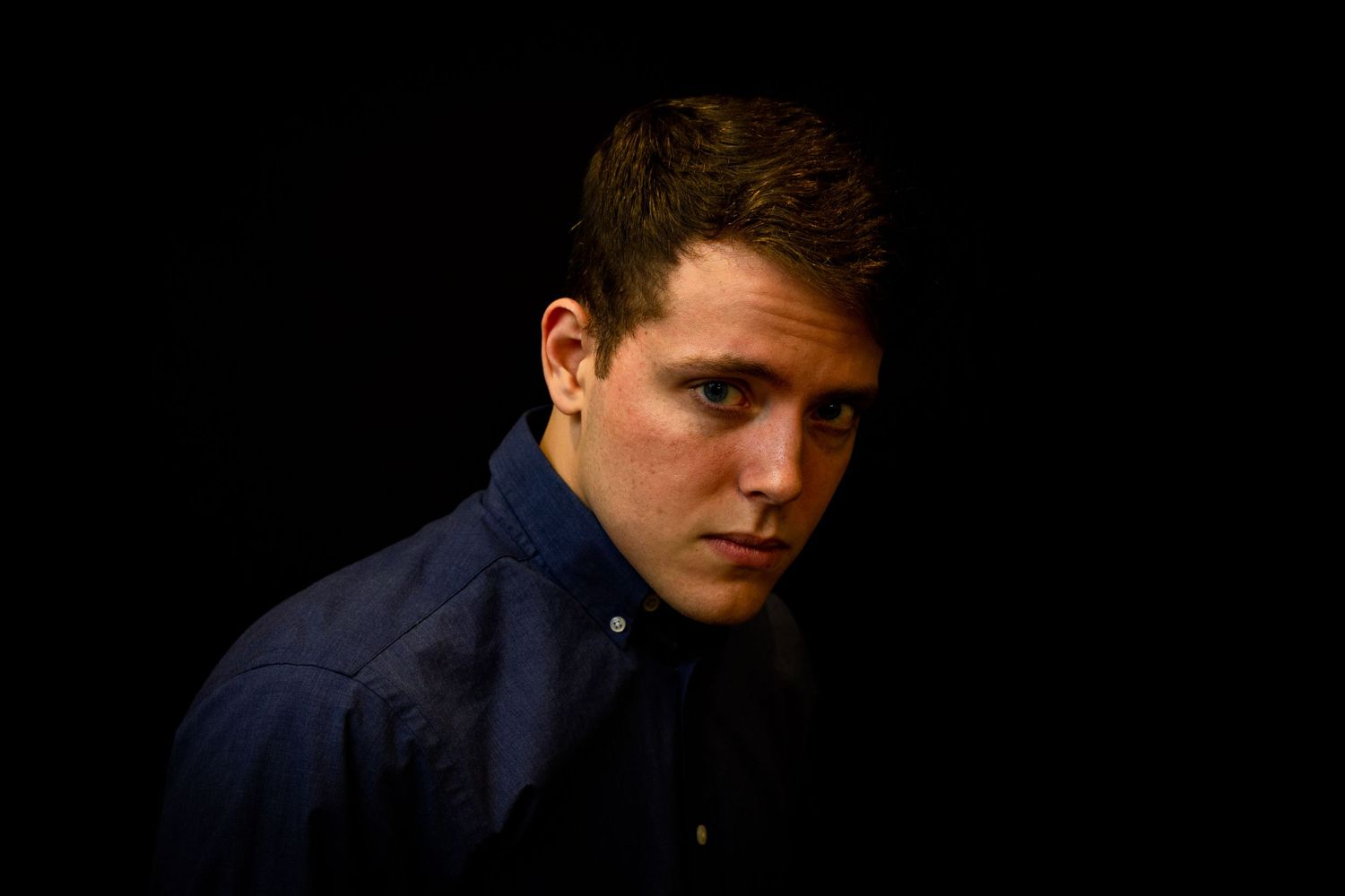 A dramatic portrait against a dark background with moody lighting.