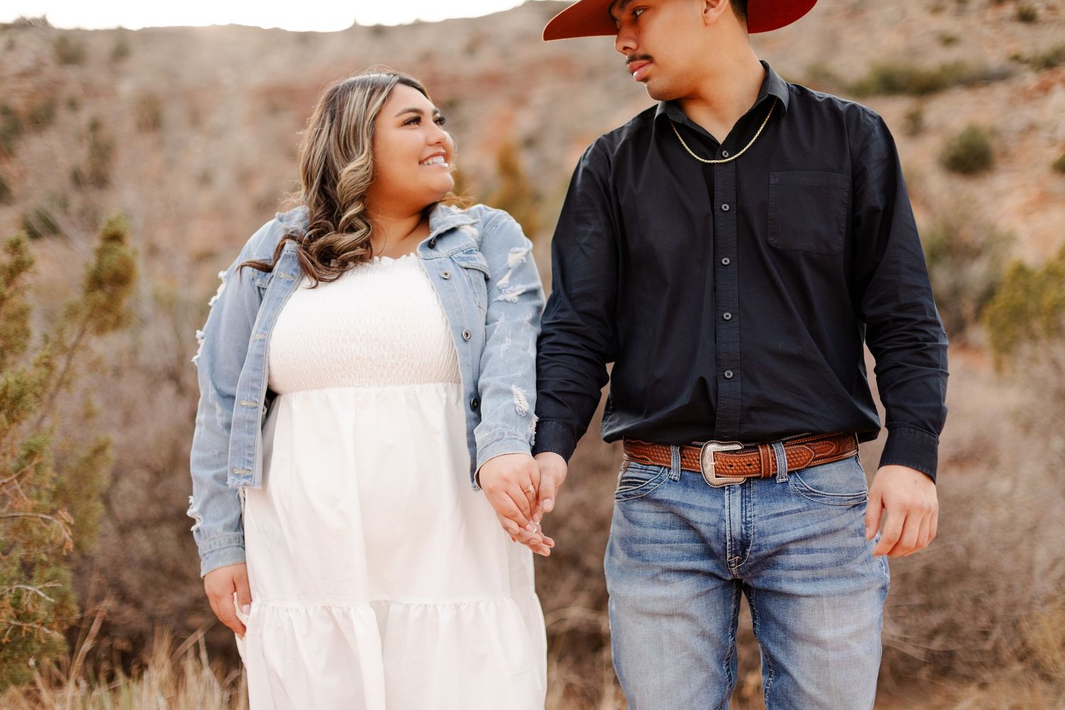 Couple in western attire sharing a tender moment during desert engagement shoot.