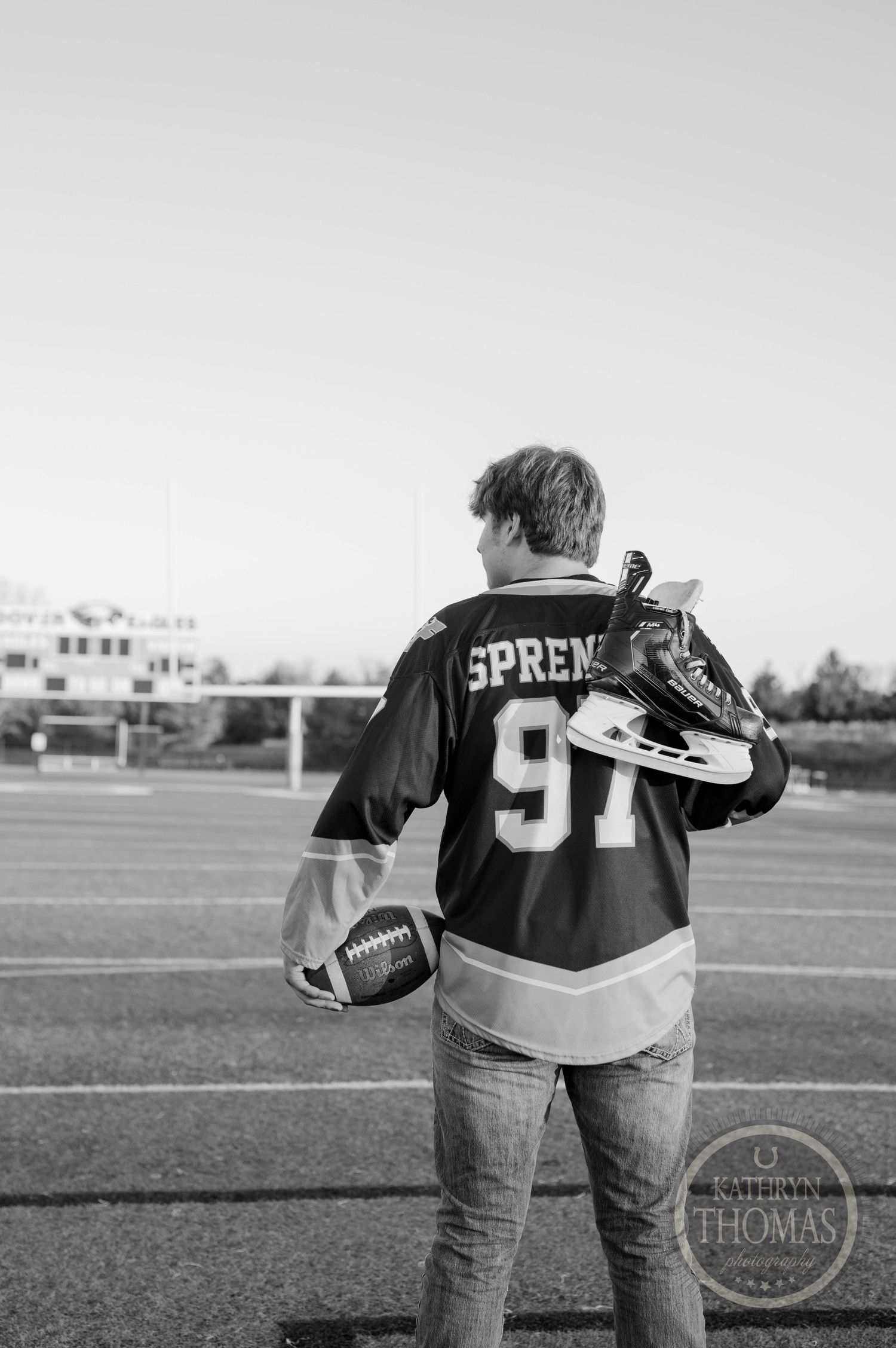 Back view of player wearing Spreen 97 jersey holding football and skates.