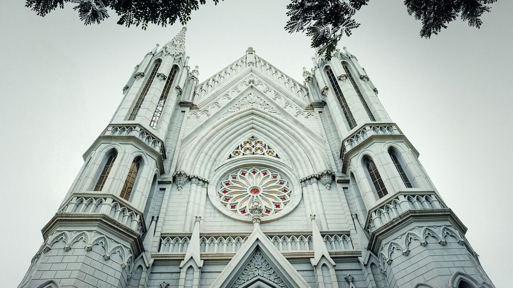 Gothic cathedral facade with ornate spires and clock tower photographed from below.