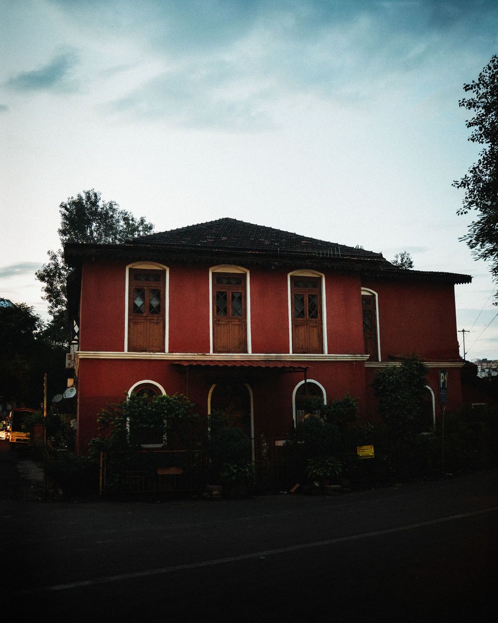 Long red brick building with boarded windows photographed at dusk against dark clouds.