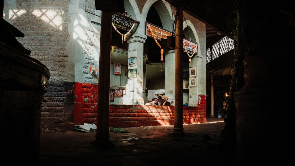 Dark interior hallway with arched columns and dramatic shadows.