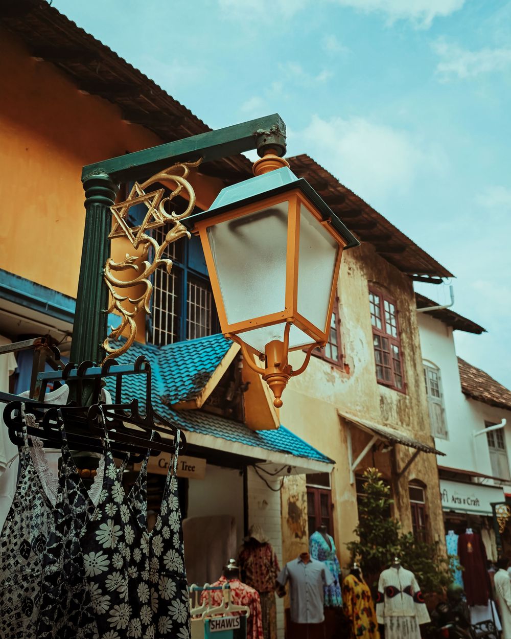 Decorative wooden angels and stars adorn the exterior of Spanish colonial style buildings with blue tiled roofs.