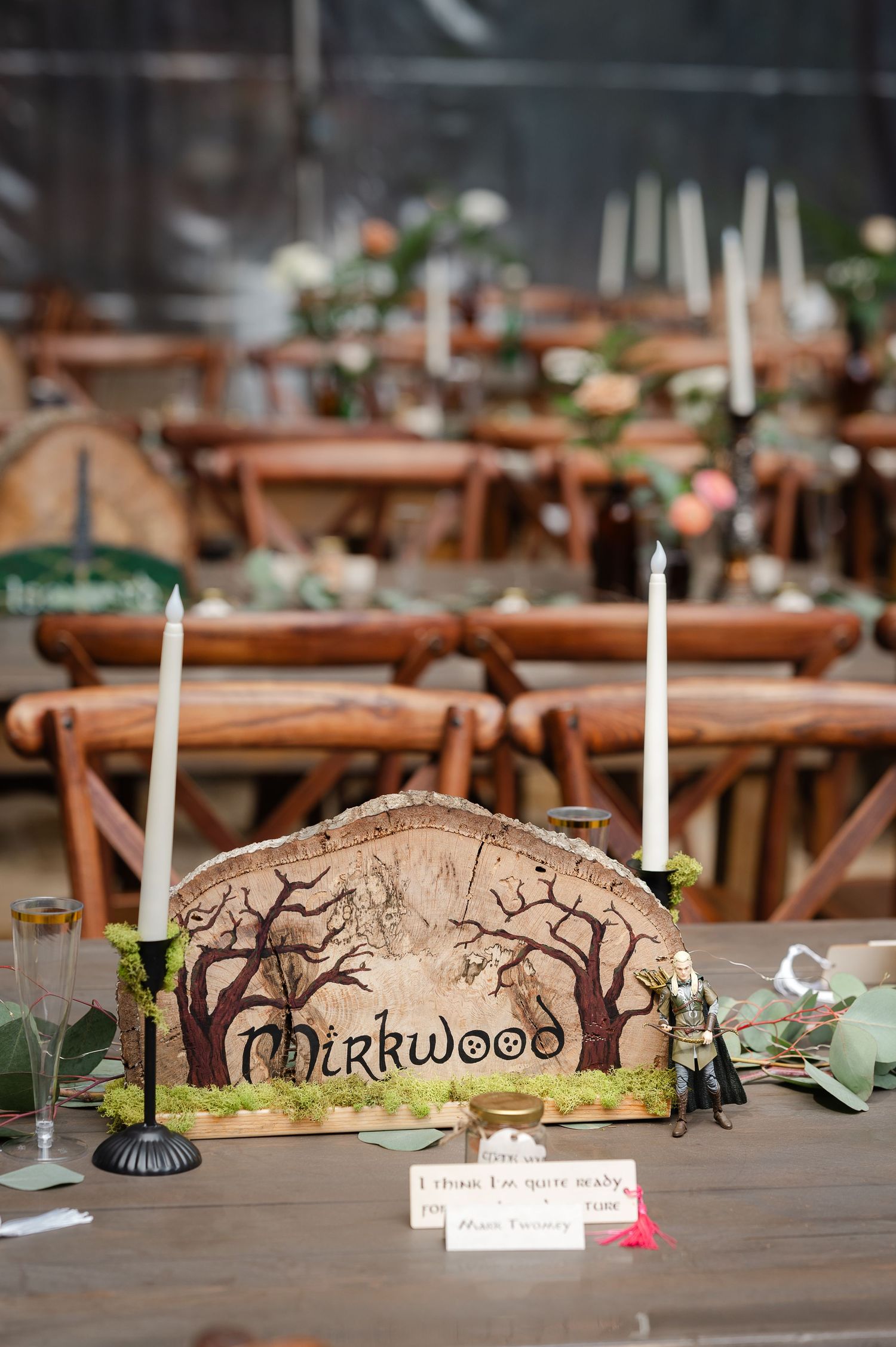 Rustic wooden cross-back chairs and tables set up under a clear tent for an elegant outdoor wedding reception.