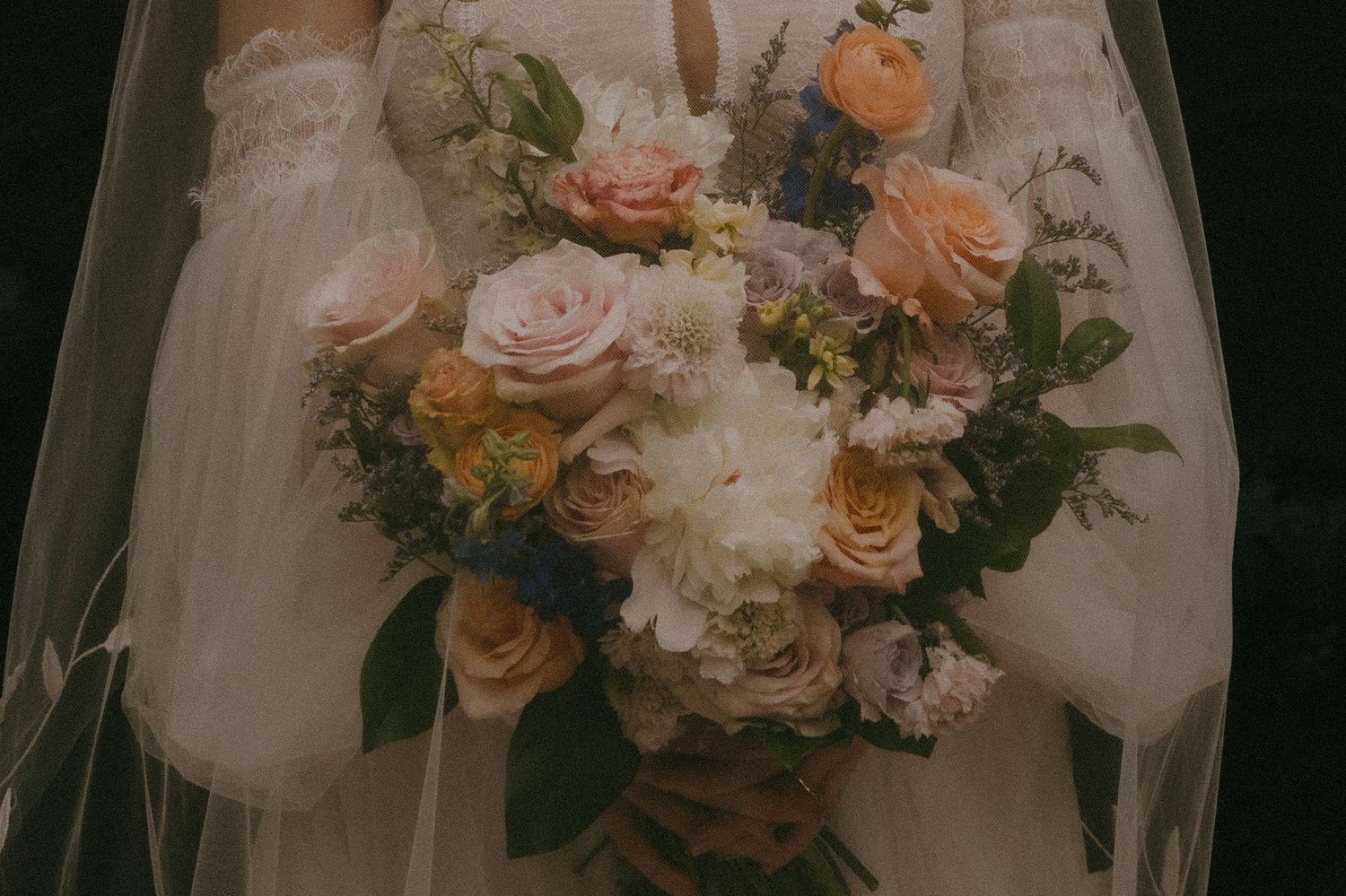Elegant bridal bouquet featuring blush roses and mixed florals against white dress fabric.