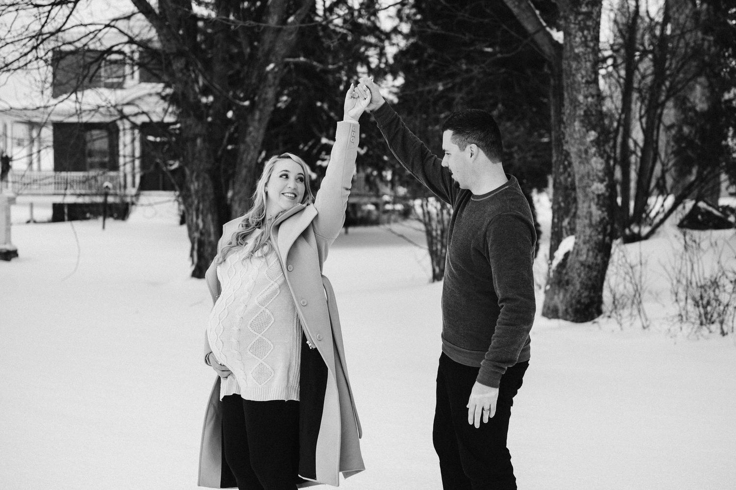 Couple having playful moment together during winter maternity photoshoot in the snow.
