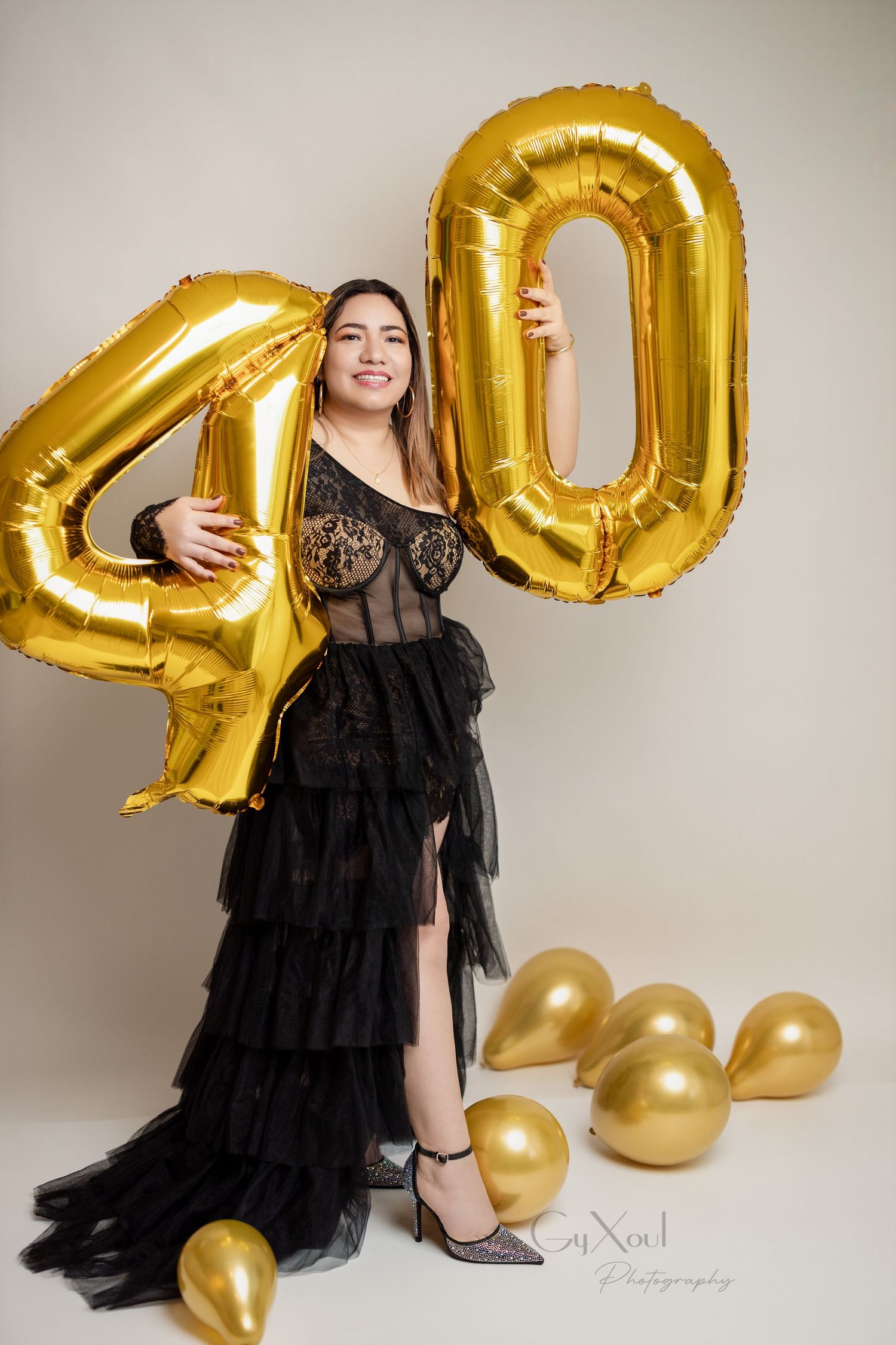A birthday celebration with large gold number 40 balloons and a black tulle gown.