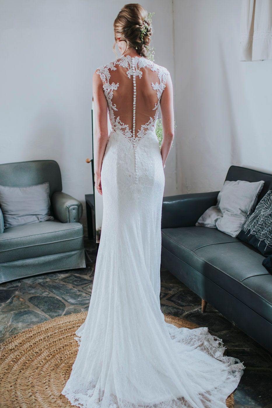Elegant wedding dress with sheer illusion back featuring delicate lace appliques and button details with flowing train.