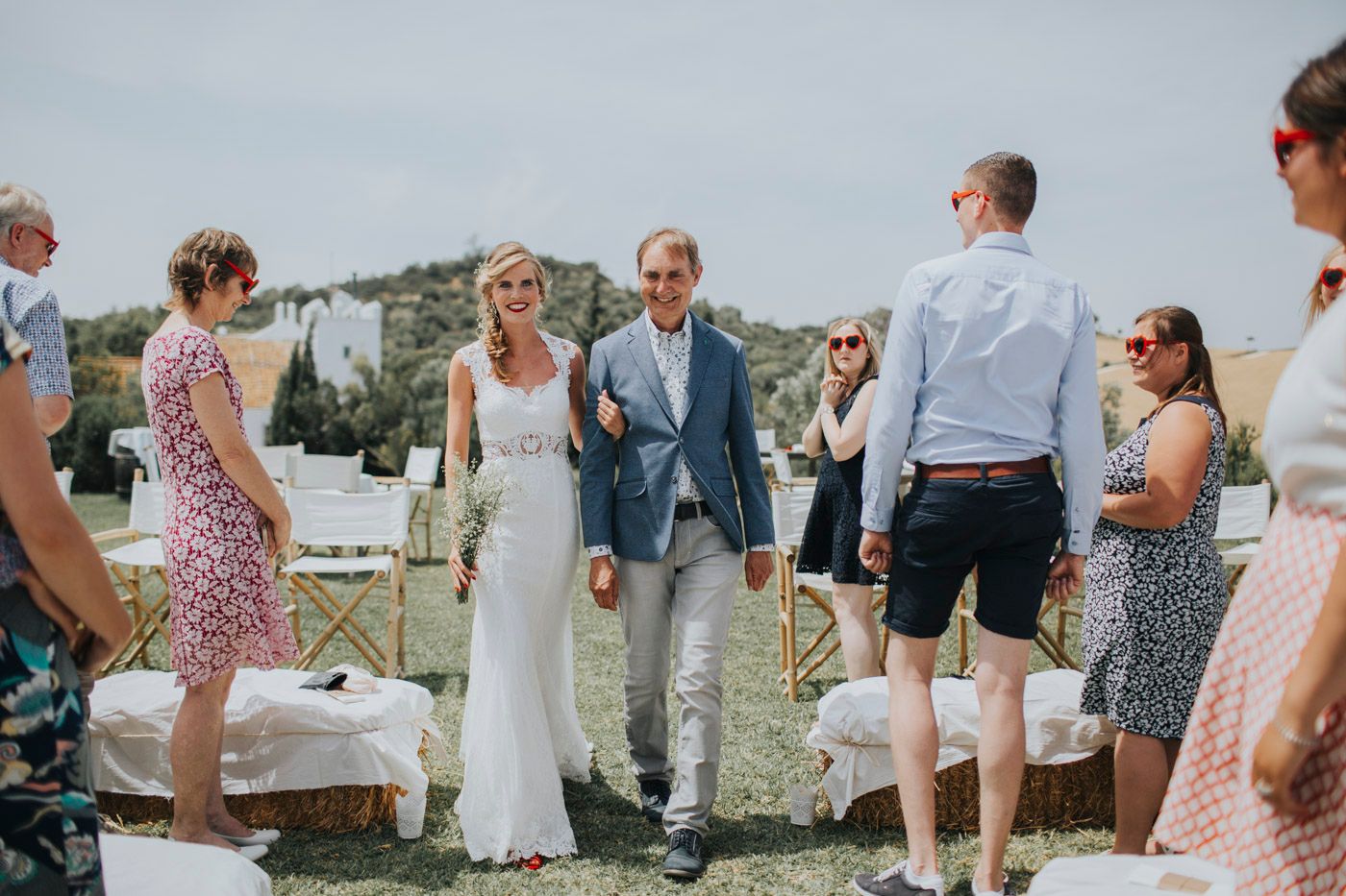 A relaxed outdoor gathering on a hillside as guests mingle during summertime festivities.