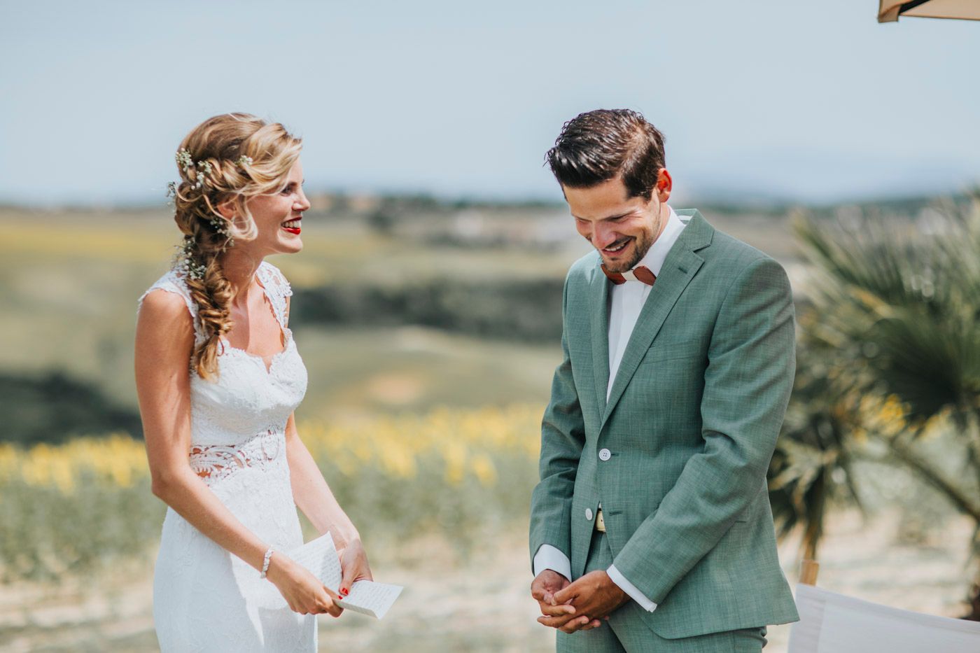 Couple sharing a joyful candid moment together during an outdoor wedding ceremony in a scenic countryside setting.