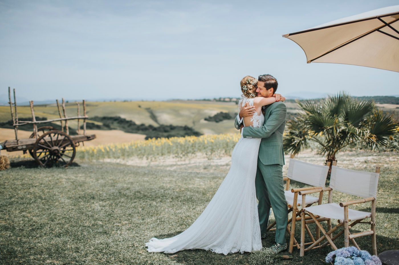 A romantic outdoor wedding ceremony in a countryside setting with vintage decor and parasol umbrella.