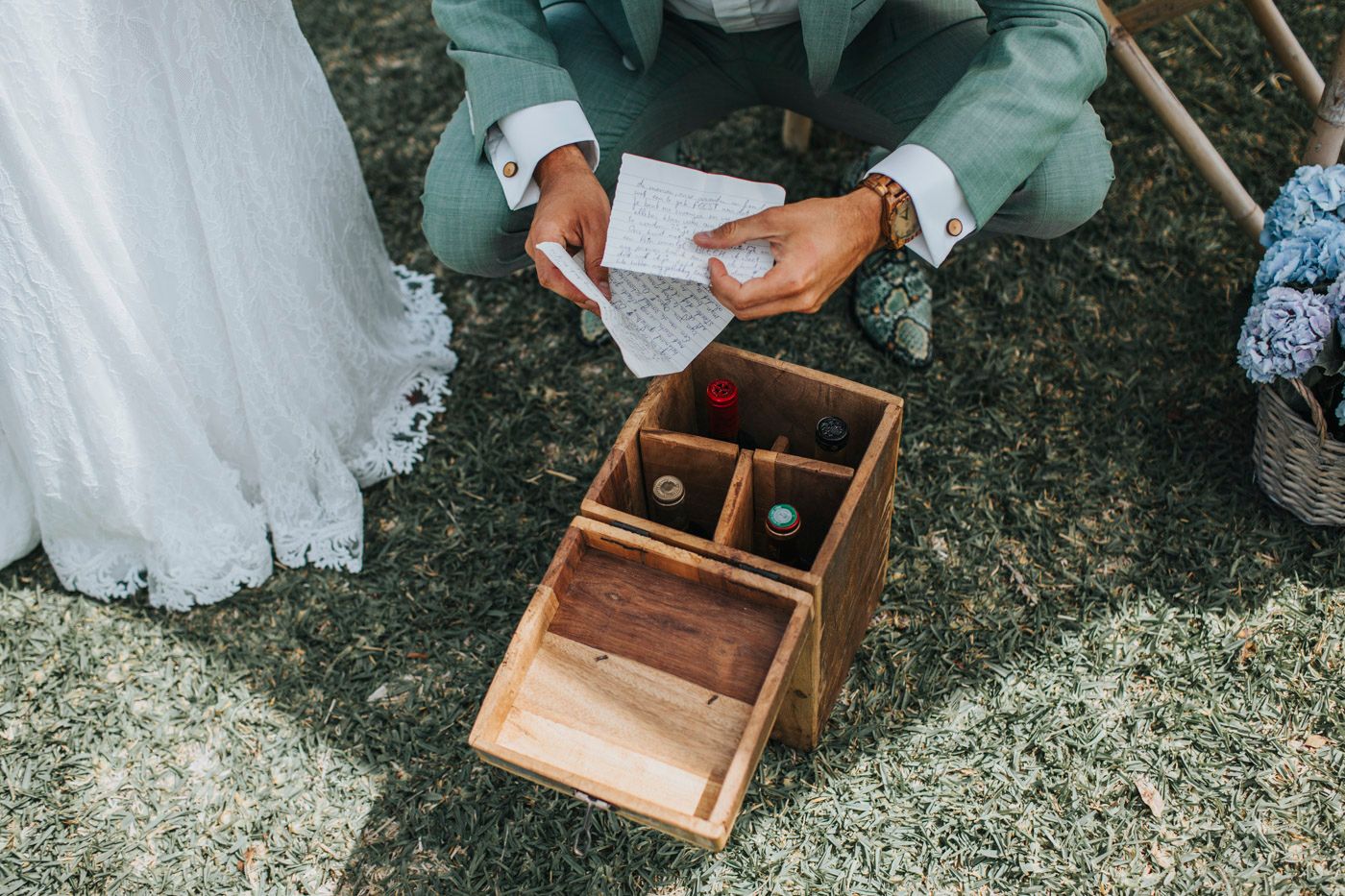 Close-up view of wedding ceremony details showing hands opening a wooden ring box.