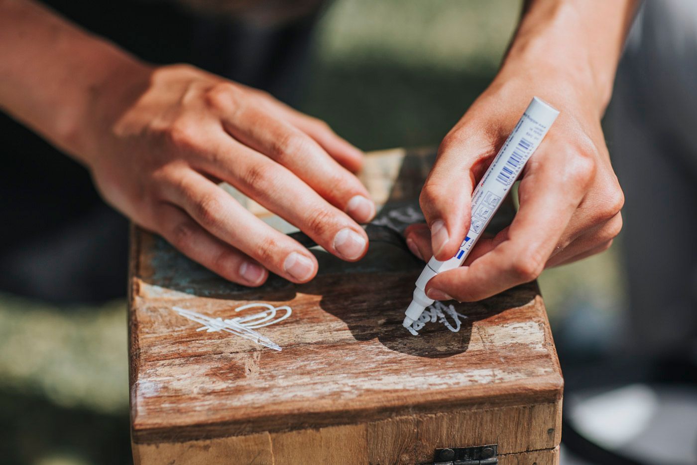 Hands writing or signing on a rustic wooden surface during a wedding ceremony.