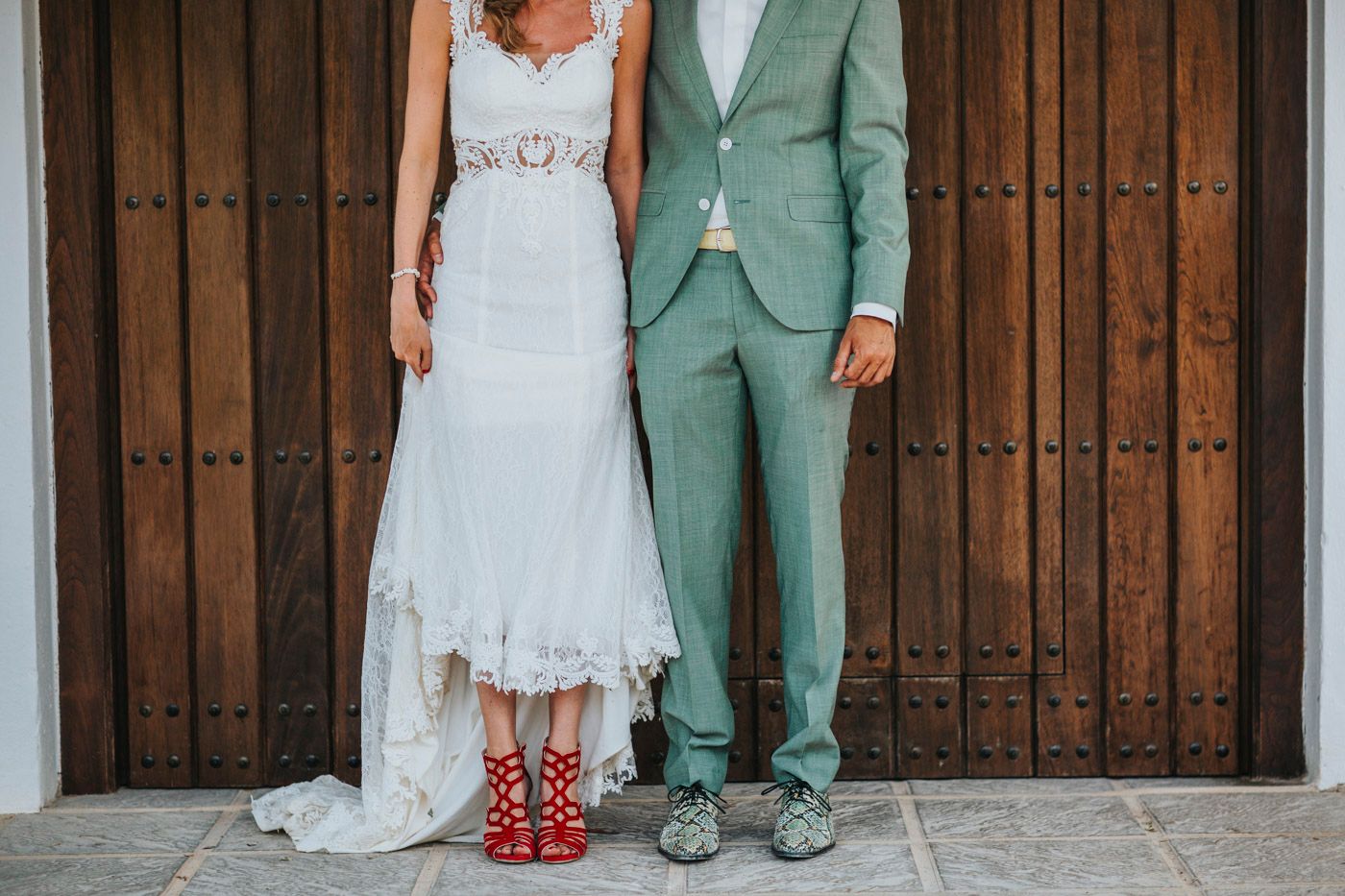 Wedding couple showing off their creative footwear with bride in polka dot socks and groom in mint green suit.