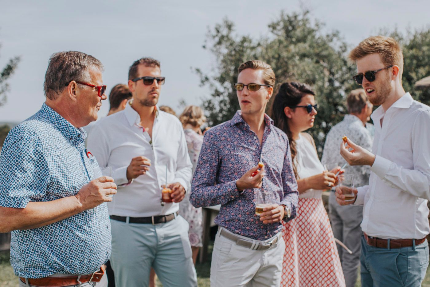 A group of friends enjoying drinks and conversation during an outdoor summer gathering.