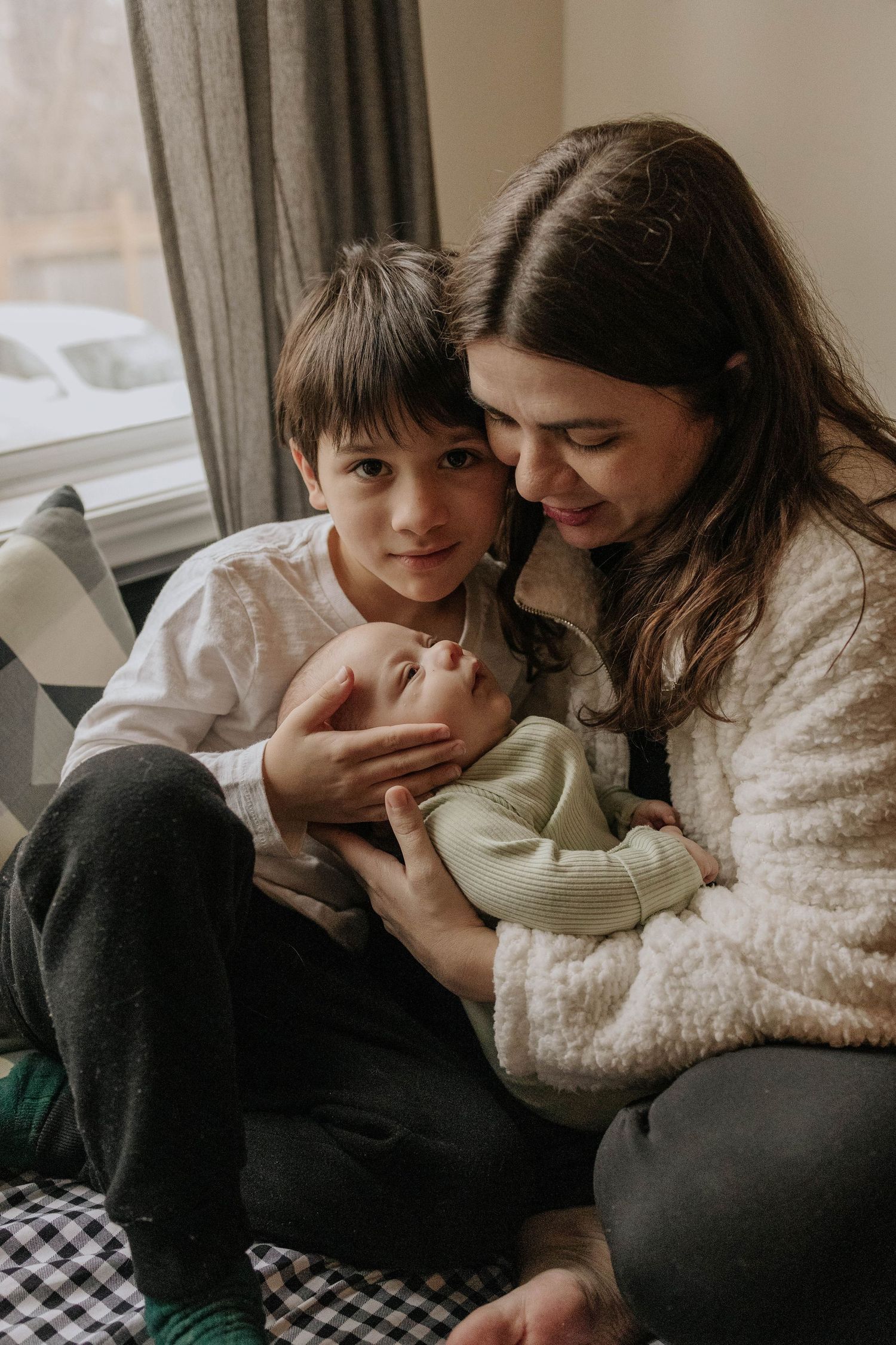 mother and ther 8 years old son looking to her newborn baby in their living room, in Etobicoke, Toronto