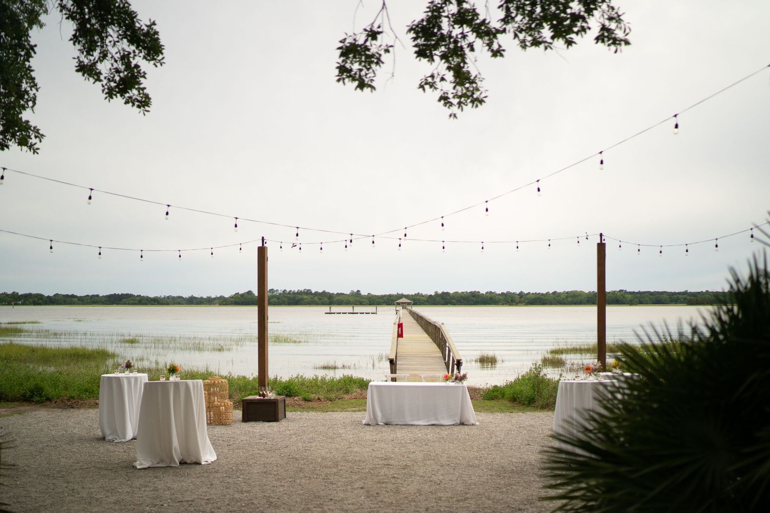A white tablecloth reception setup in front of a private pier at a Charleston wedding