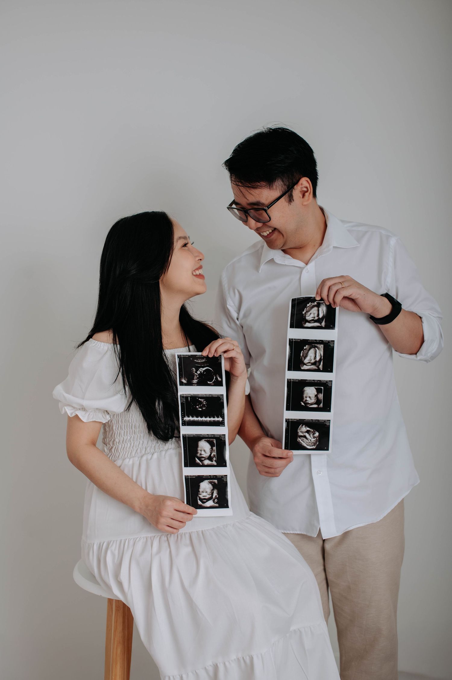 Couple showing ultrasound photos during pregnancy announcement photoshoot.