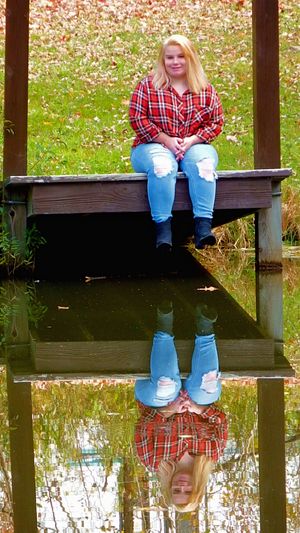Reflection photo on wooden dock over calm water during autumn season.