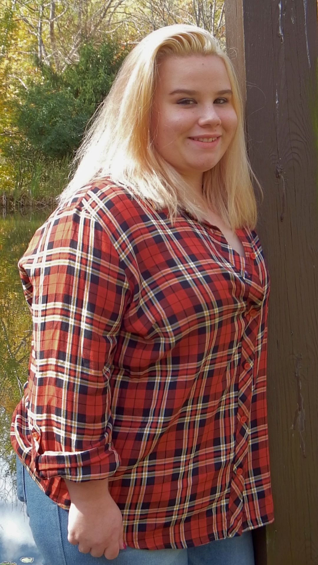 Close-up shot of red plaid flannel shirt against natural autumn background.