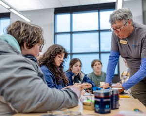 Students working on a project while an instructor provides guidance at a table.
