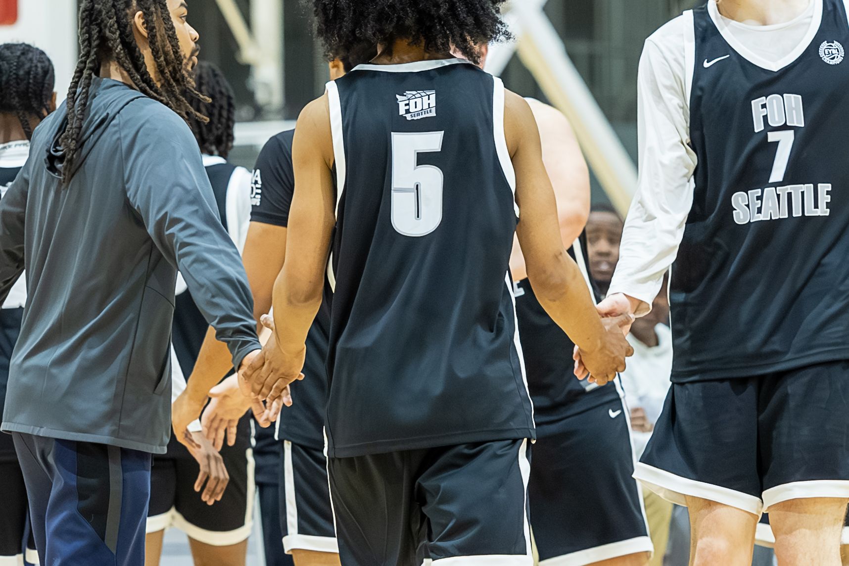 Seattle basketball players in black uniforms numbers 5 and 7 shaking hands on the court.