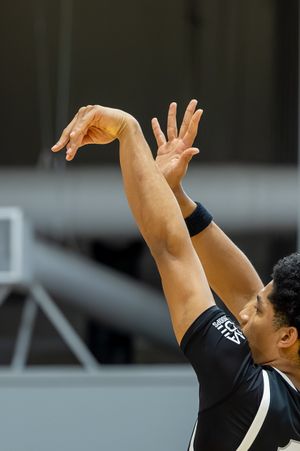 Basketball player shooting with both arms raised high during an indoor game.