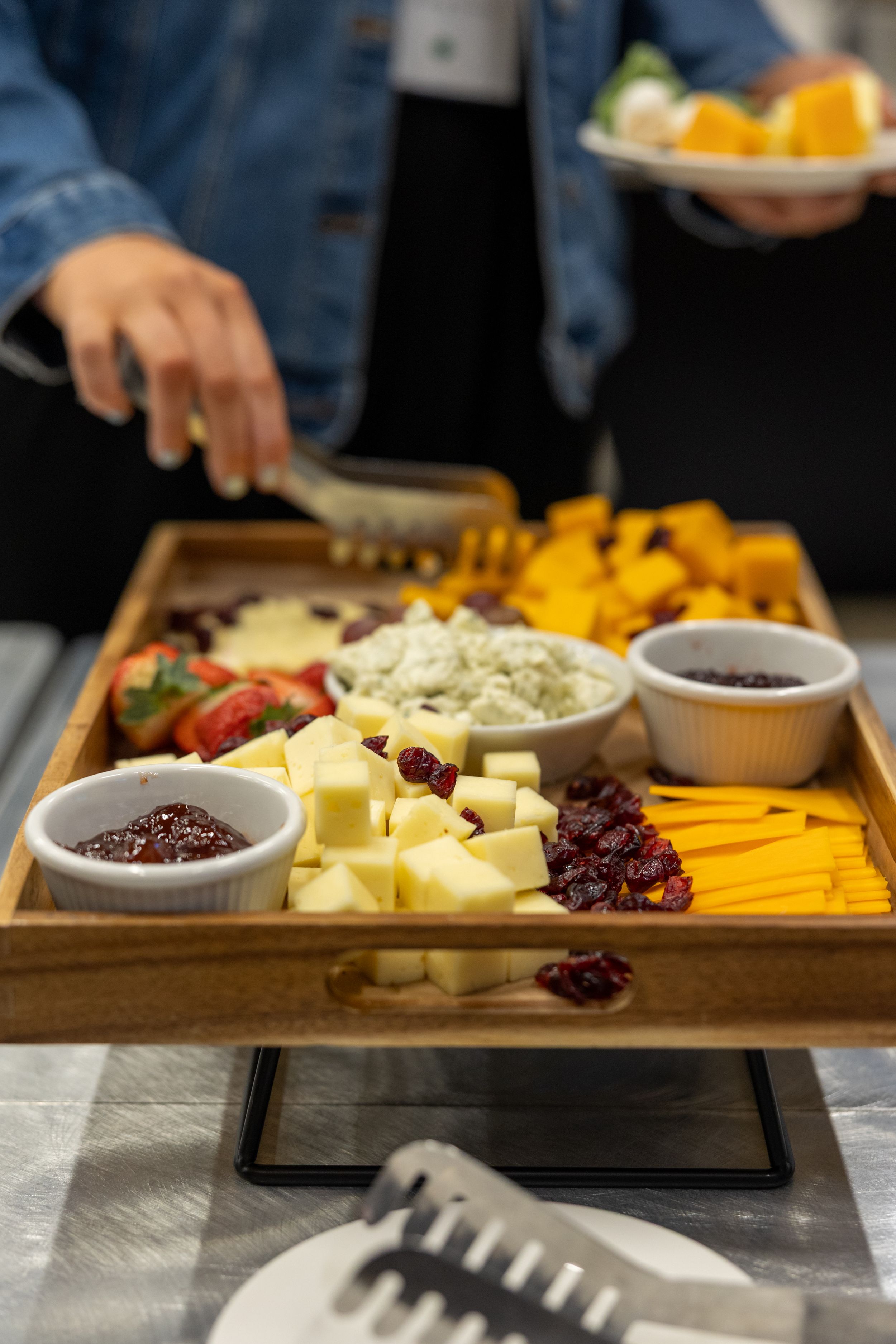 Elegant charcuterie board with cubed cheese, dried cranberries, fresh strawberries, blue cheese dip, and jam served on a wooden tray.