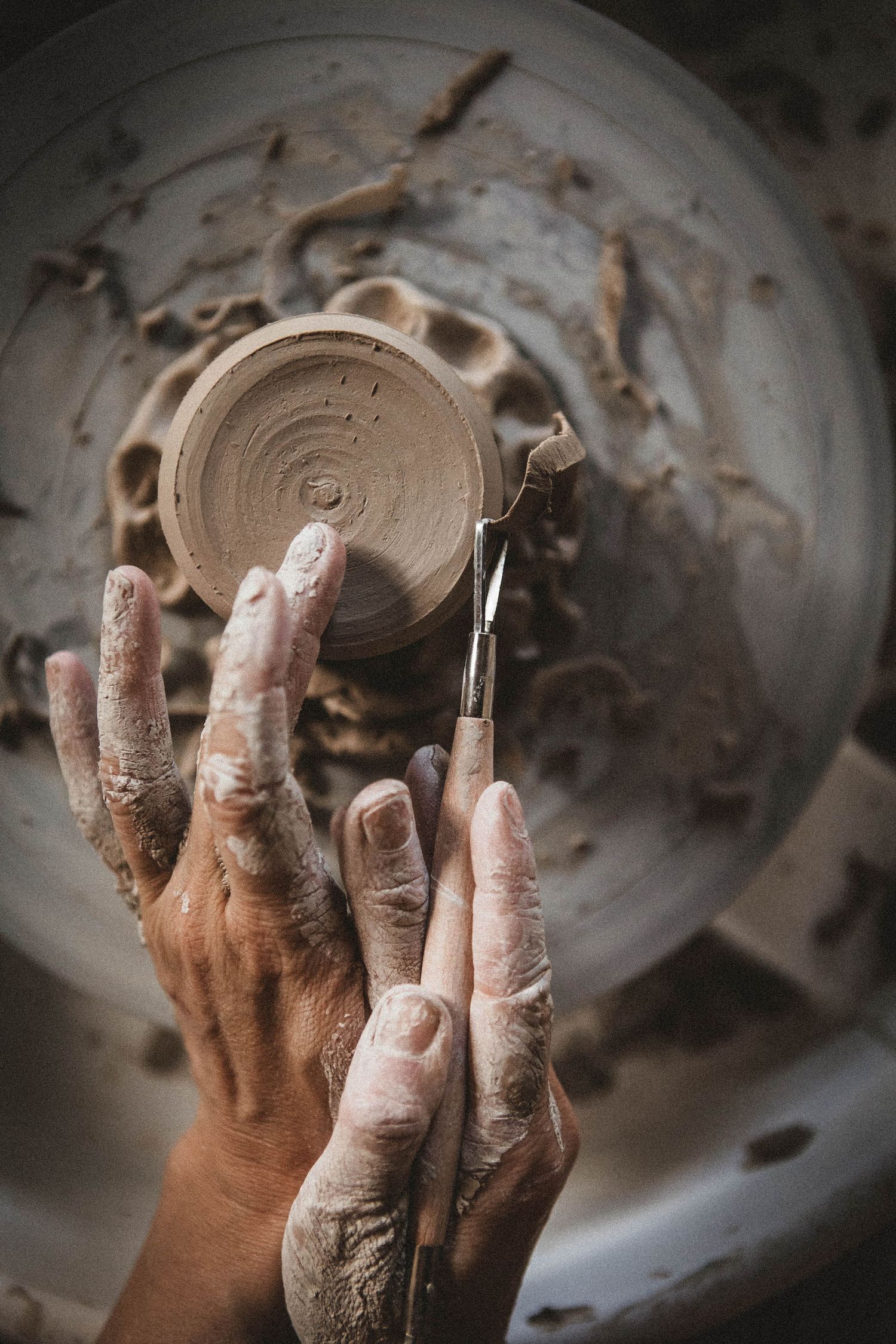 Clay-covered hands shaping pottery on a wheel, capturing the artistic process in detail.