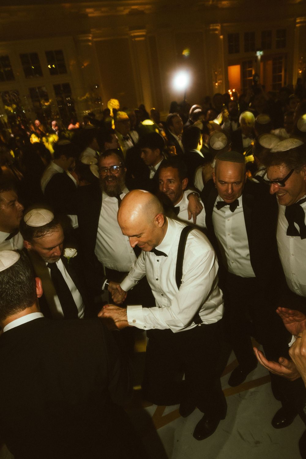 A crowd of formally dressed people in bow ties and suits gathered at an indoor celebration.