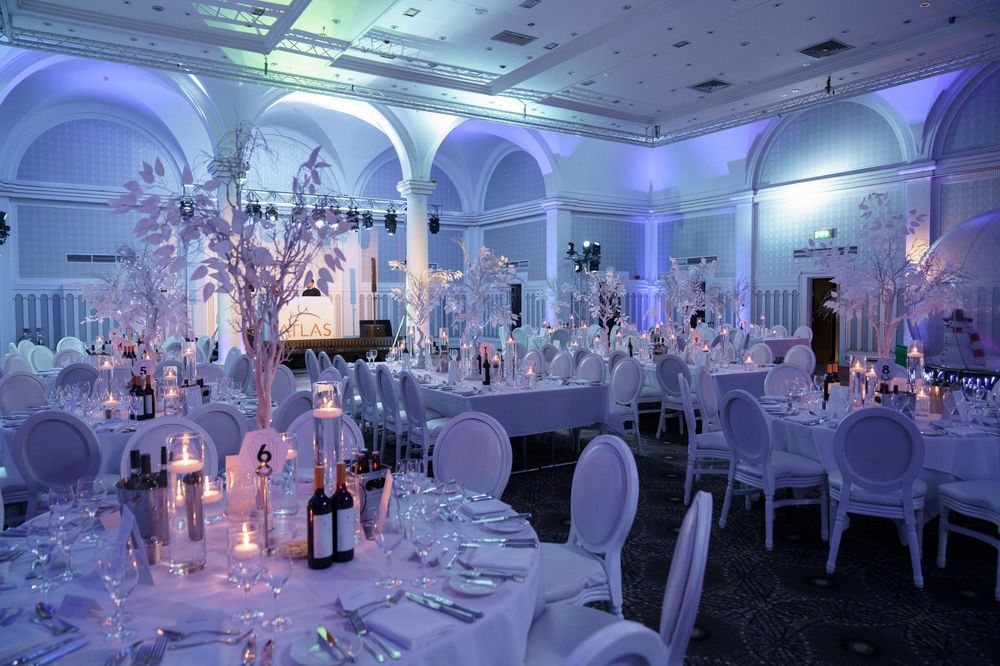 Elegant winter wonderland wedding reception with white decor, blue lighting and crystal centerpieces in a grand ballroom.