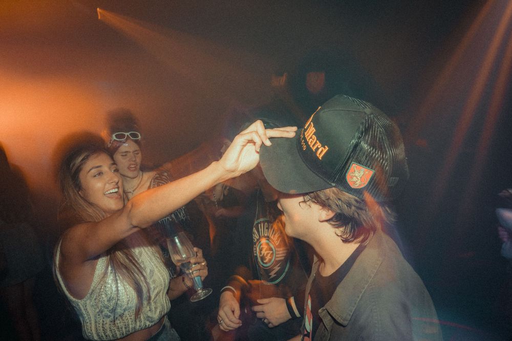 Party-goers sharing drinks and having fun in a dark club environment.