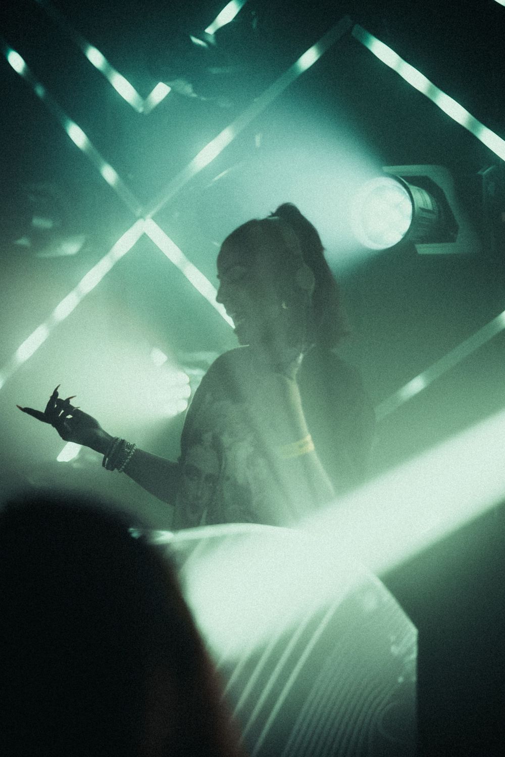 Silhouette of a performer amid dramatic crossed light beams in a smoky venue.