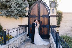 Couple posing in front of rustic wooden church doors during wedding.