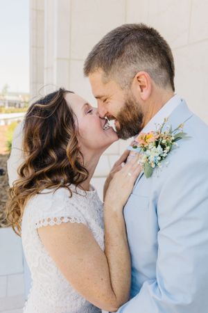 Intimate moment between newlyweds in light blue suit and white lace dress.
