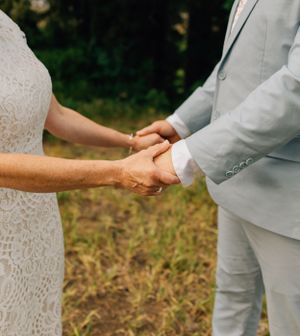 Close-up of bride and groom holding hands during outdoor wedding ceremony.