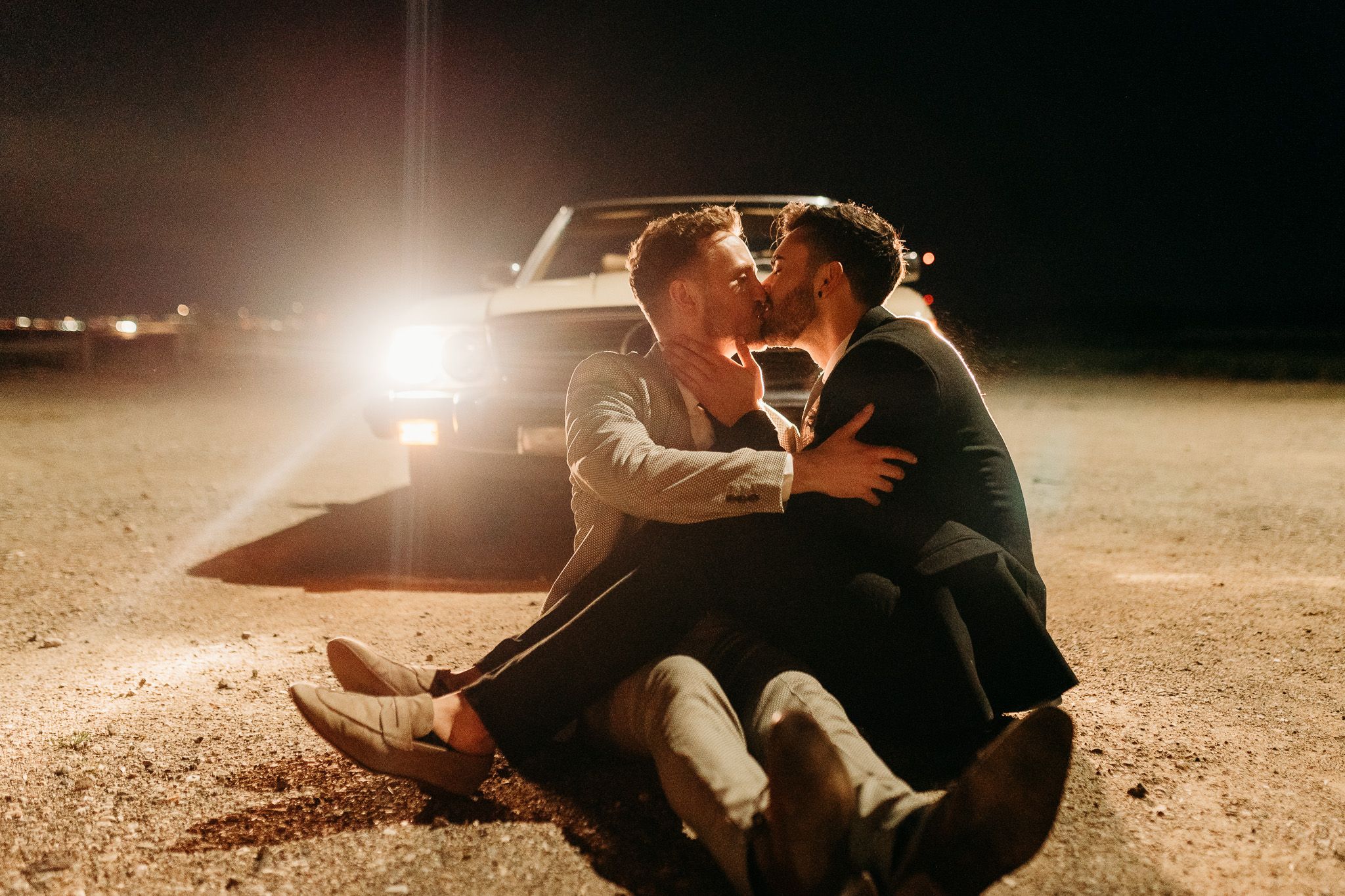 Romantic nighttime couple portrait with car headlights in background.