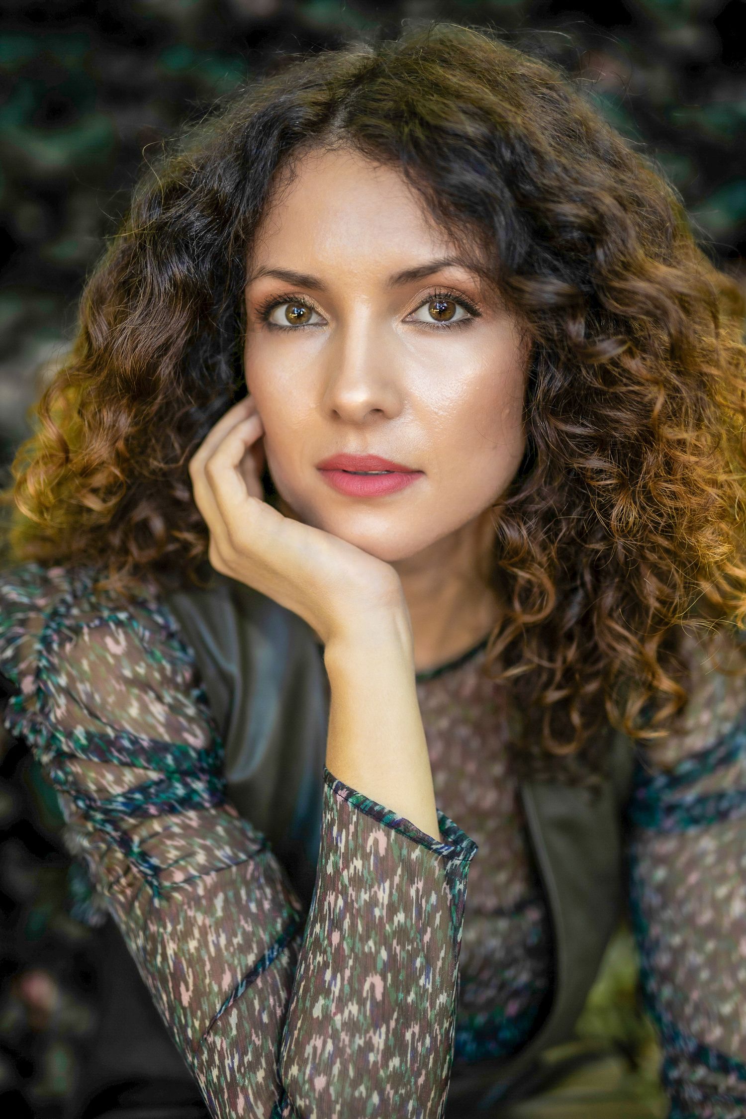 Natural light headshot of woman resting her chin on her hand in an outdoor setting, Essex-Country photographer.