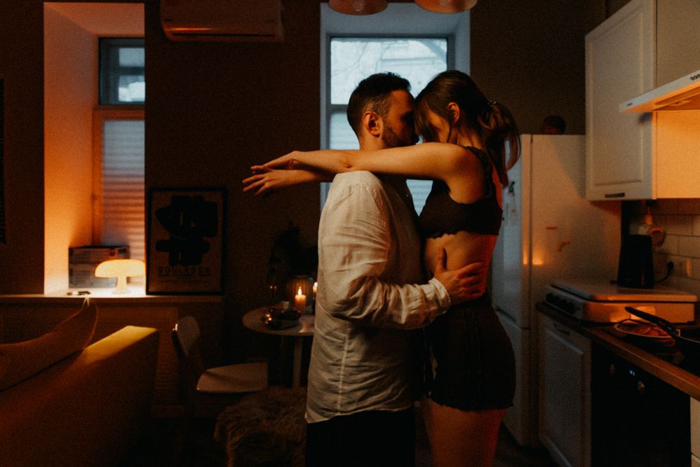 Couple dancing intimately in dimly lit kitchen with romantic atmosphere.
