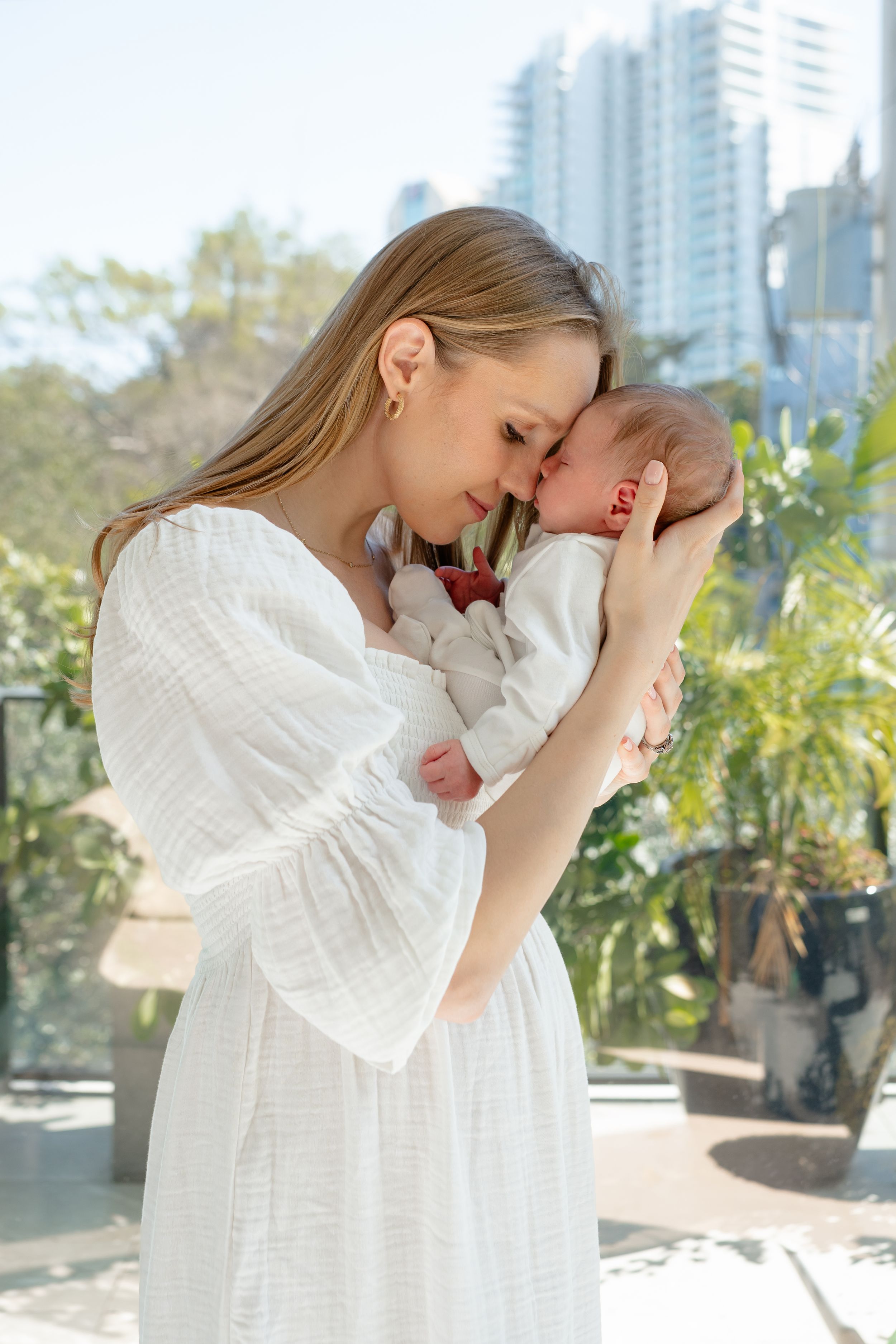 Series of tender moments captured near modern city buildings with white flowing dress and natural lighting.