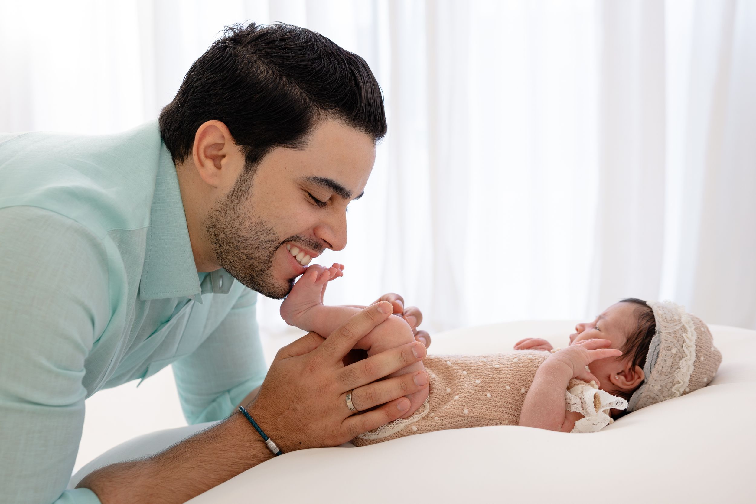 Tender moment between parent and newborn baby in soft natural lighting.