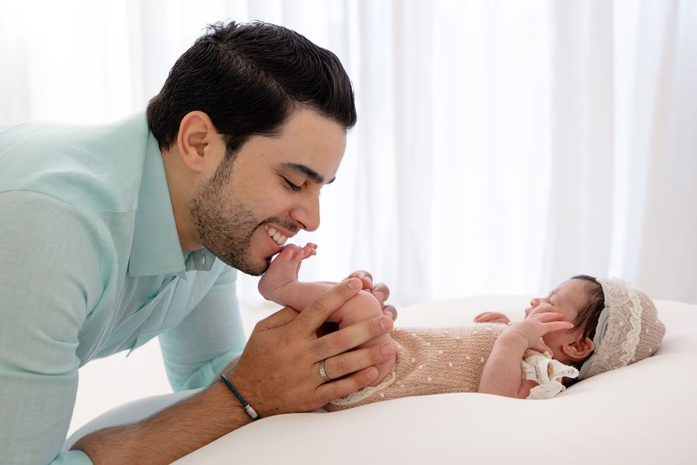 Tender moment between parent and newborn baby in soft natural lighting.