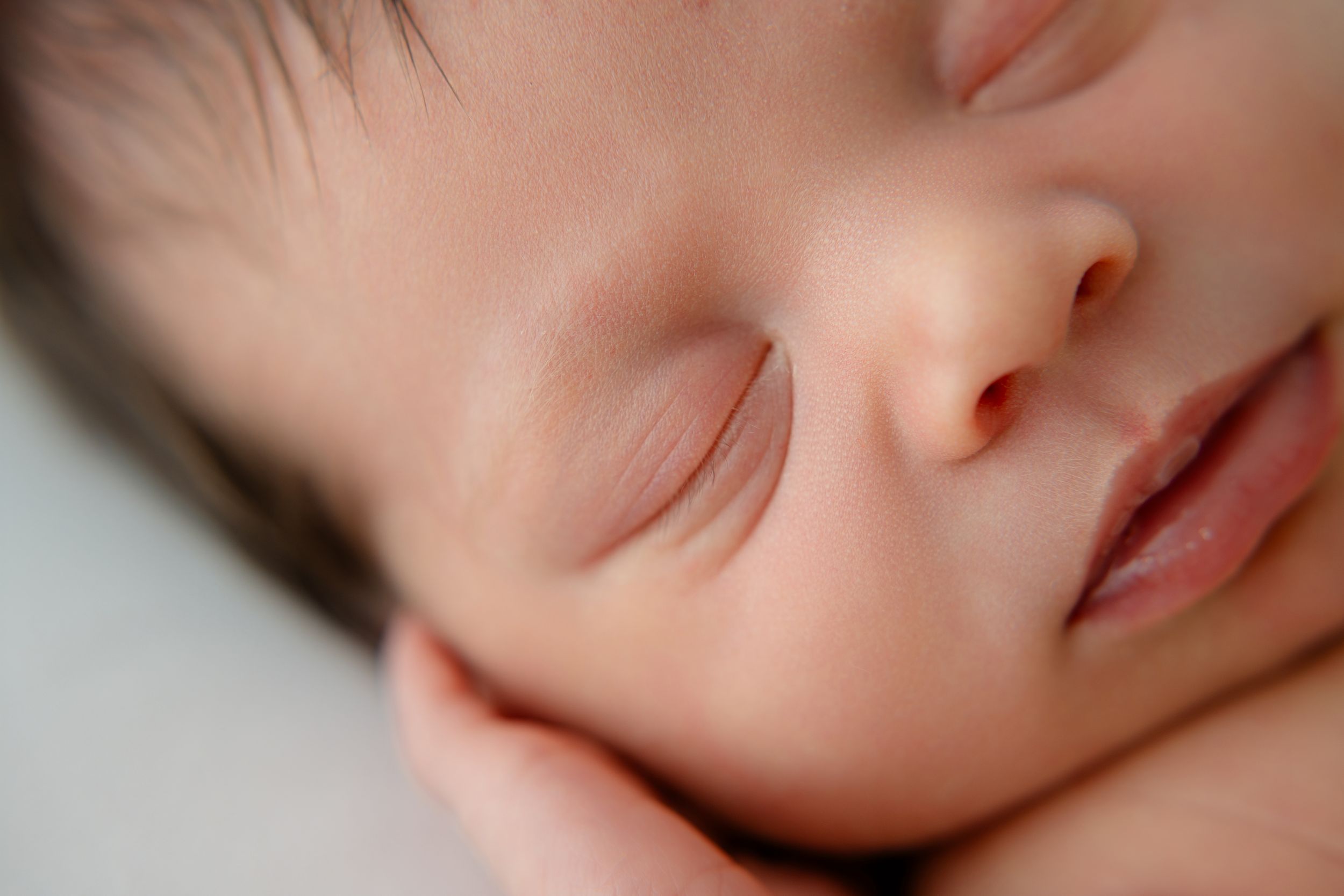 Close-up macro photos of a sleeping baby's facial features showing nose, lips, and skin details in soft lighting.
