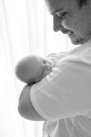 Four tender moments captured in black and white show a loving parent sharing a tender moment with their baby.